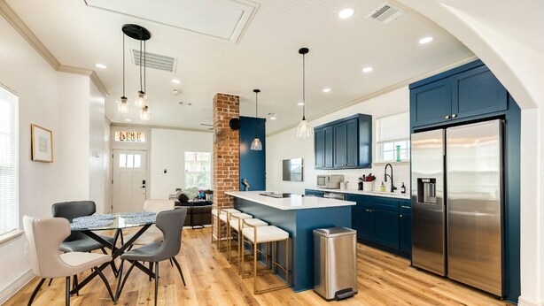A modern kitchen with a central island, bar stools, and stainless steel appliances.