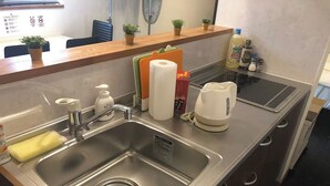 A modern kitchen with a stainless steel sink, a kettle, and a small countertop with a plant and a bottle of hand soap. - GoodHome Toyokawa (Hakodate)