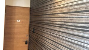 A room with a wooden door labeled 'A', a textured wall, and a light fixture. - GoodHome Toyokawa (Hakodate)