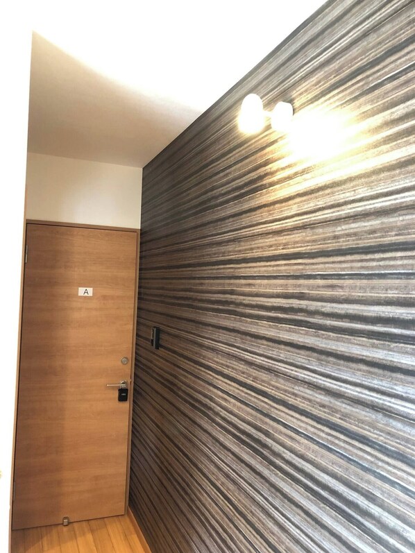 A room with a wooden door labeled 'A', a textured wall, and a light fixture. - GoodHome Toyokawa (Hakodate)