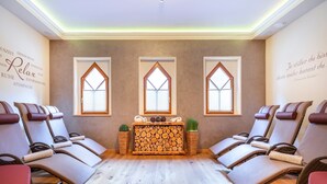 A spa room with wooden flooring, massage chairs, a central fireplace, and large windows. - Apartment in Kleinarl near Ski Slopes (Kleinarl)