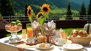 A table set for breakfast with a mountain view, including plates, cups, and a basket of bread. - Apartment in Kleinarl near Ski Slopes (Kleinarl)