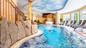 An indoor swimming pool with a waterfall feature, surrounded by lounge chairs and a staircase. - Apartment in Kleinarl near Ski Slopes (Kleinarl)