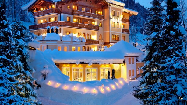 A multi-story hotel with balconies, surrounded by snow-covered trees and a mountainous backdrop. - Apartment in Kleinarl near Ski Slopes (Kleinarl)