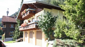 A traditional chalet with a wooden facade, balconies with flower boxes, and a mountain backdrop. - Apartment in Kleinarl near Ski Lift (Kleinarl)