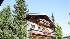 A multi-story building with balconies, surrounded by tall evergreen trees. - Apartment in Kleinarl near Ski Lift (Kleinarl)