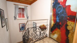 Una escalera con barandilla metálica, una ventana con cortinas y un cuadro en la pared.