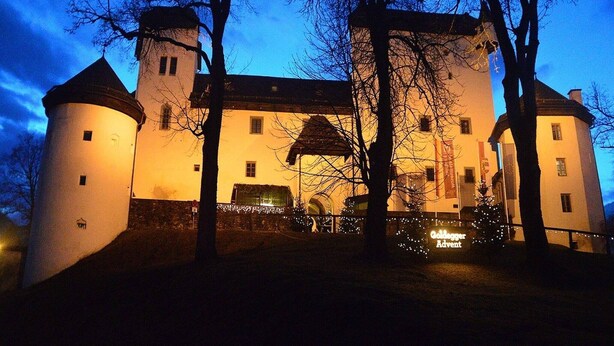 Un castillo histórico con dos torres, un edificio central y un letrero que dice 'Goldene Advet'.