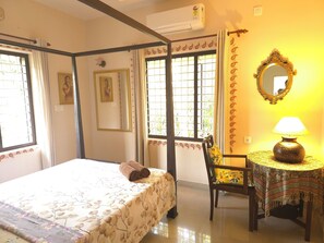 A bedroom with a bed, a chair, a table with a lamp, and a window with curtains. - Bella Boutique Homestay (Alappuzha)