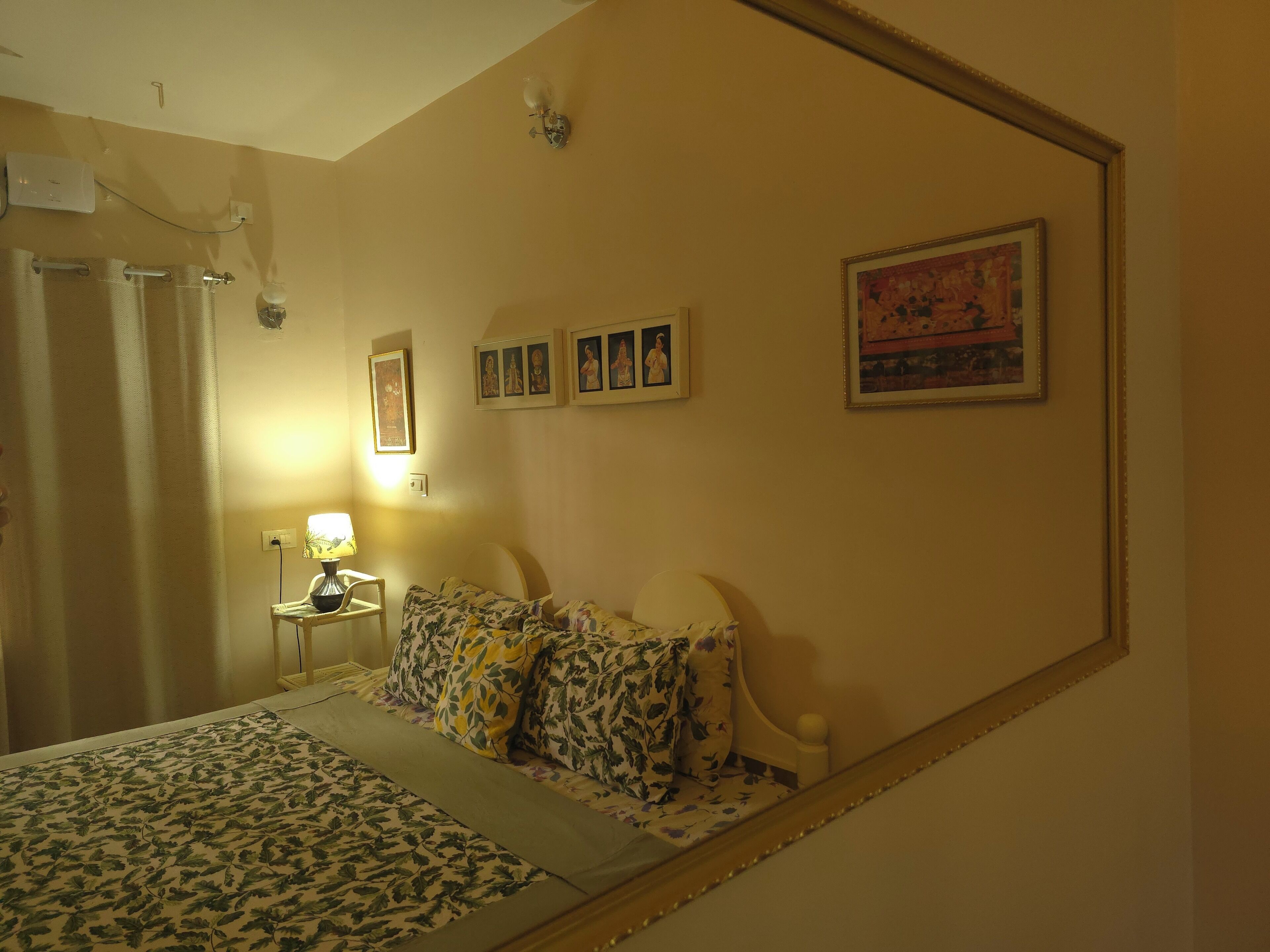 Un dormitorio con cama, mesita de noche, lámpara y cuadros en la pared.