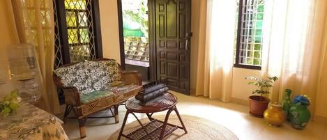 A room with a sofa, a chair, a table with a lace tablecloth, a water dispenser, and a potted plant.