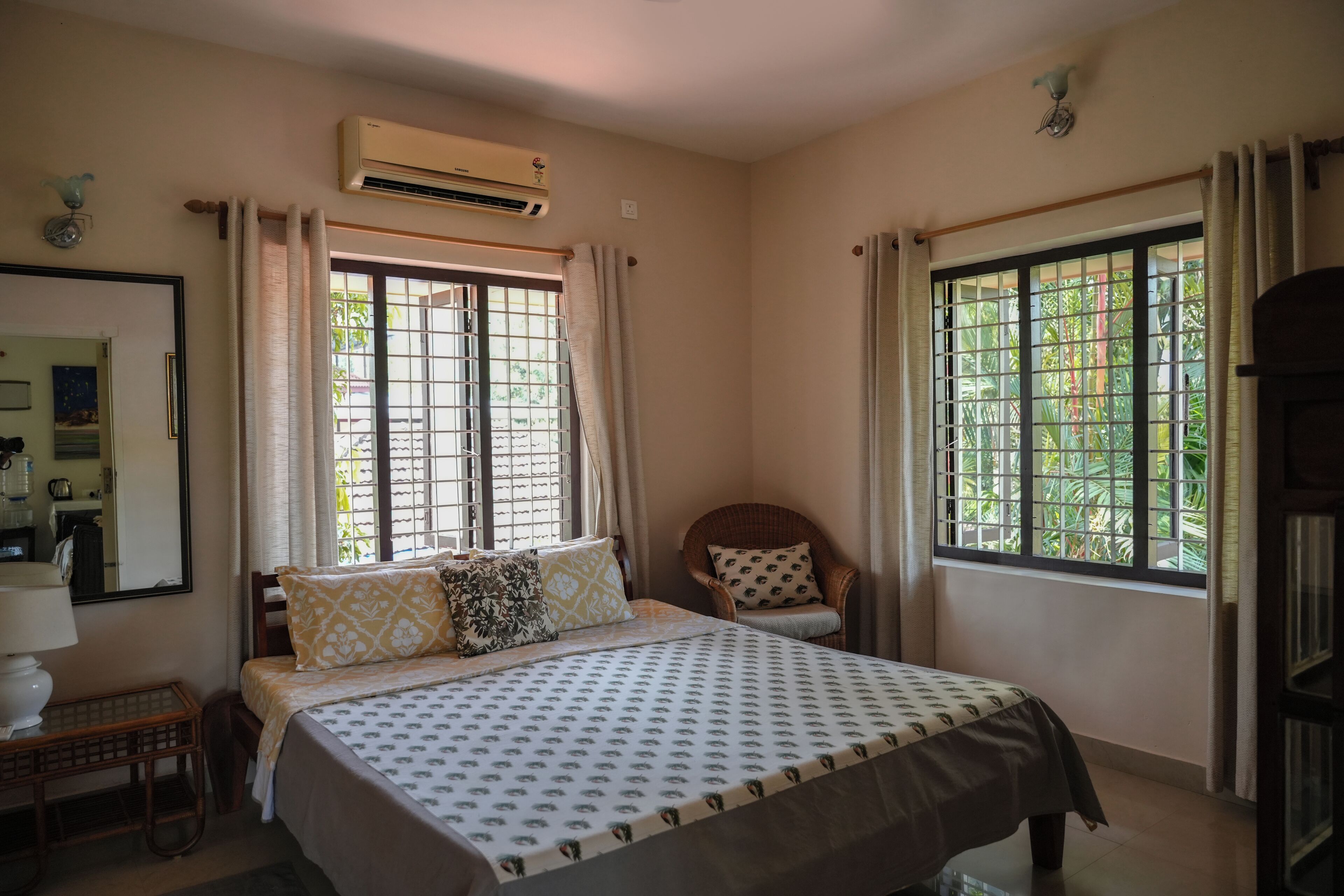 A bedroom with a bed, a chair, a desk, and two windows with curtains.