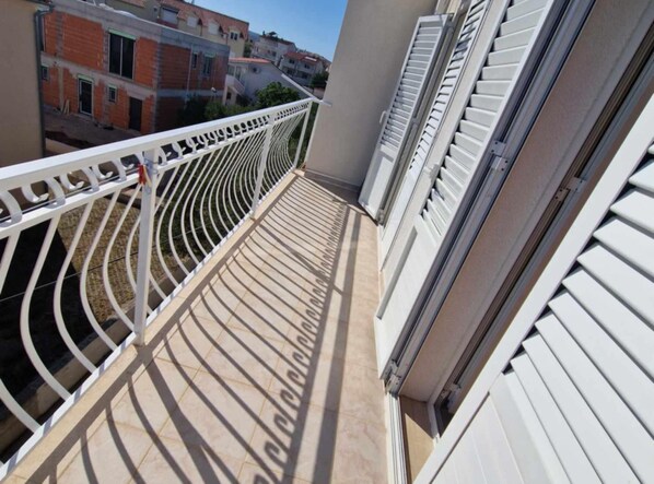 A balcony with a white metal railing and a view of neighboring buildings. - Apartments Dana (Vodice)