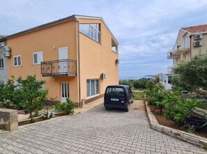 A two-story residential building with a car parked in front.