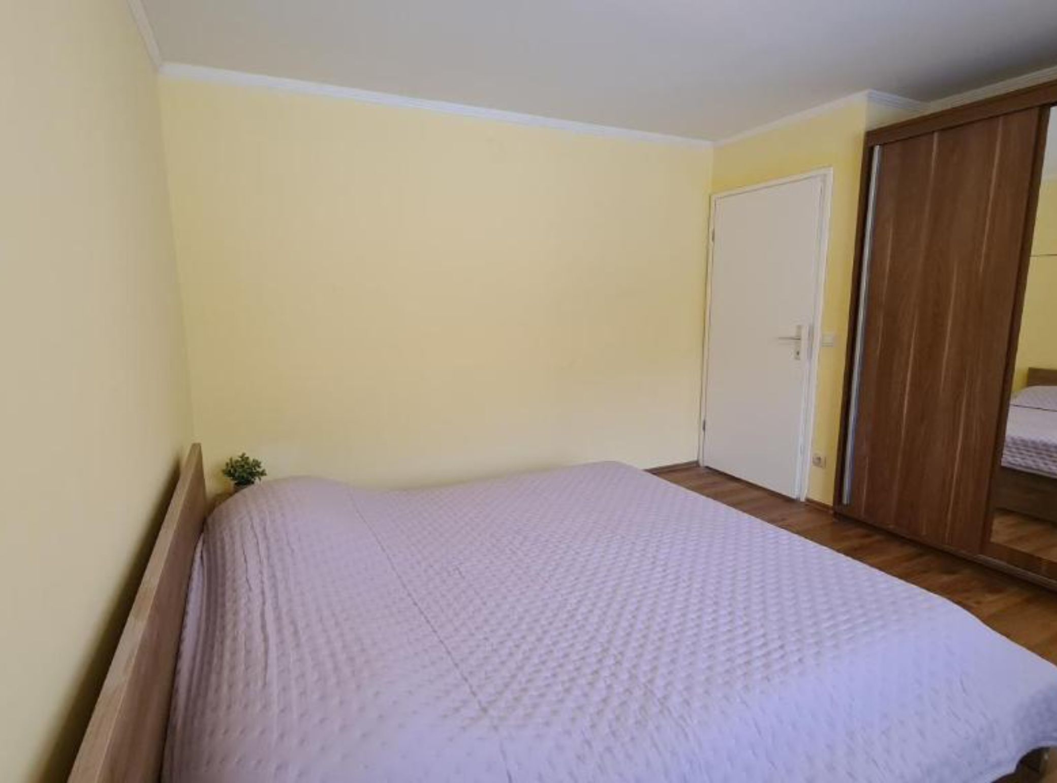A bedroom with a bed, a wardrobe, and a door.