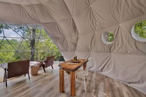 A geodesic dome structure with a wooden table and chairs, large windows, and a view of greenery. - Nottely River Retreat | Fire Pit (Murphy)