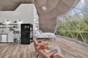 A modern, spacious interior with a kitchen, seating area, and large windows offering a view of the outdoors. - Nottely River Retreat | Fire Pit (Murphy)