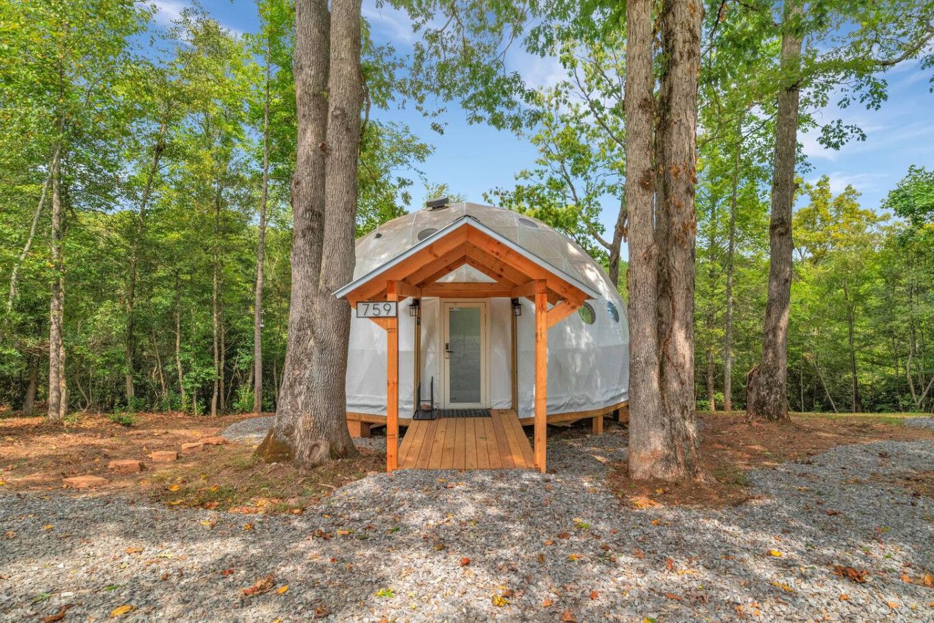 A treehouse with a wooden deck and a door, surrounded by a forest.