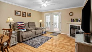 A living room with a sofa, two lamps, a fireplace, and a ceiling fan. - Fantastic Single Level Ranch Layout, Fenced Backyard w/ Large Deck, New Decor and Furnishing (Hillsboro)