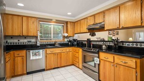 A kitchen with wooden cabinets, a stove, and a refrigerator. - Fantastic Single Level Ranch Layout, Fenced Backyard w/ Large Deck, New Decor and Furnishing (Hillsboro)