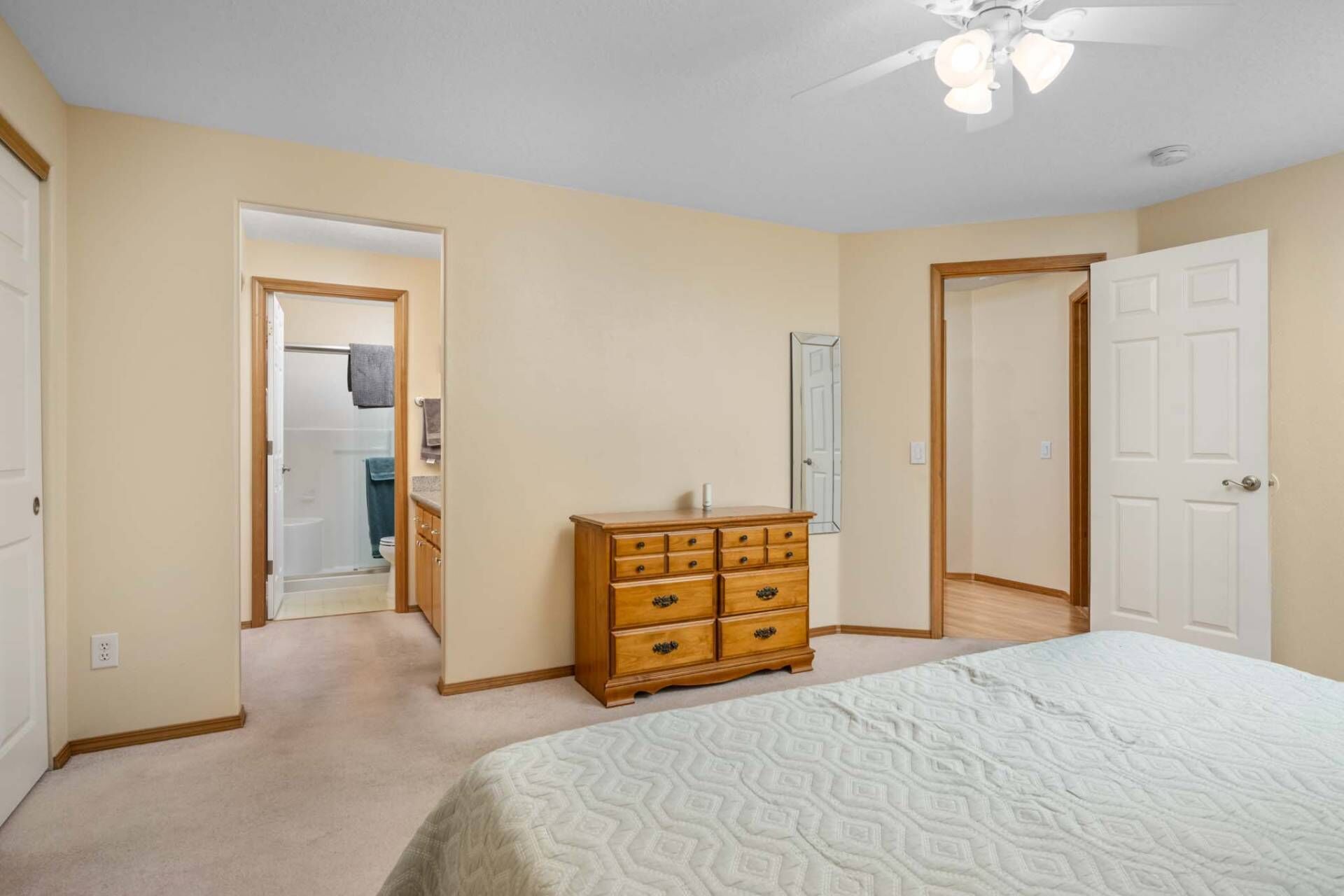 Un dormitorio con cama, cómoda de madera y ventilador de techo.