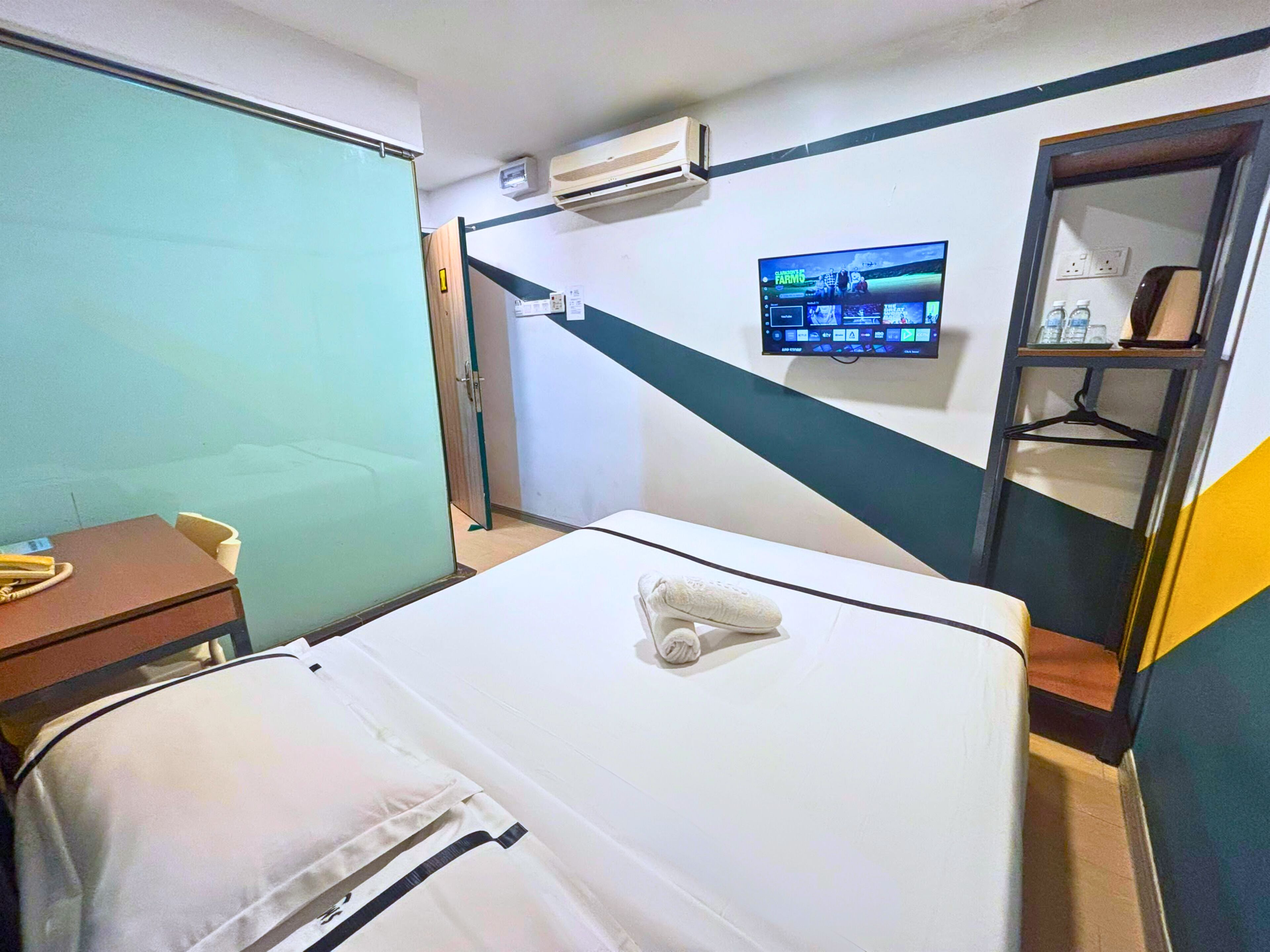 Habitación de hotel con cama, escritorio, televisor montado en la pared y aire acondicionado.