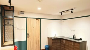 Une cuisine de taille réduite, avec un meuble en bois, un évier et une bouilloire.