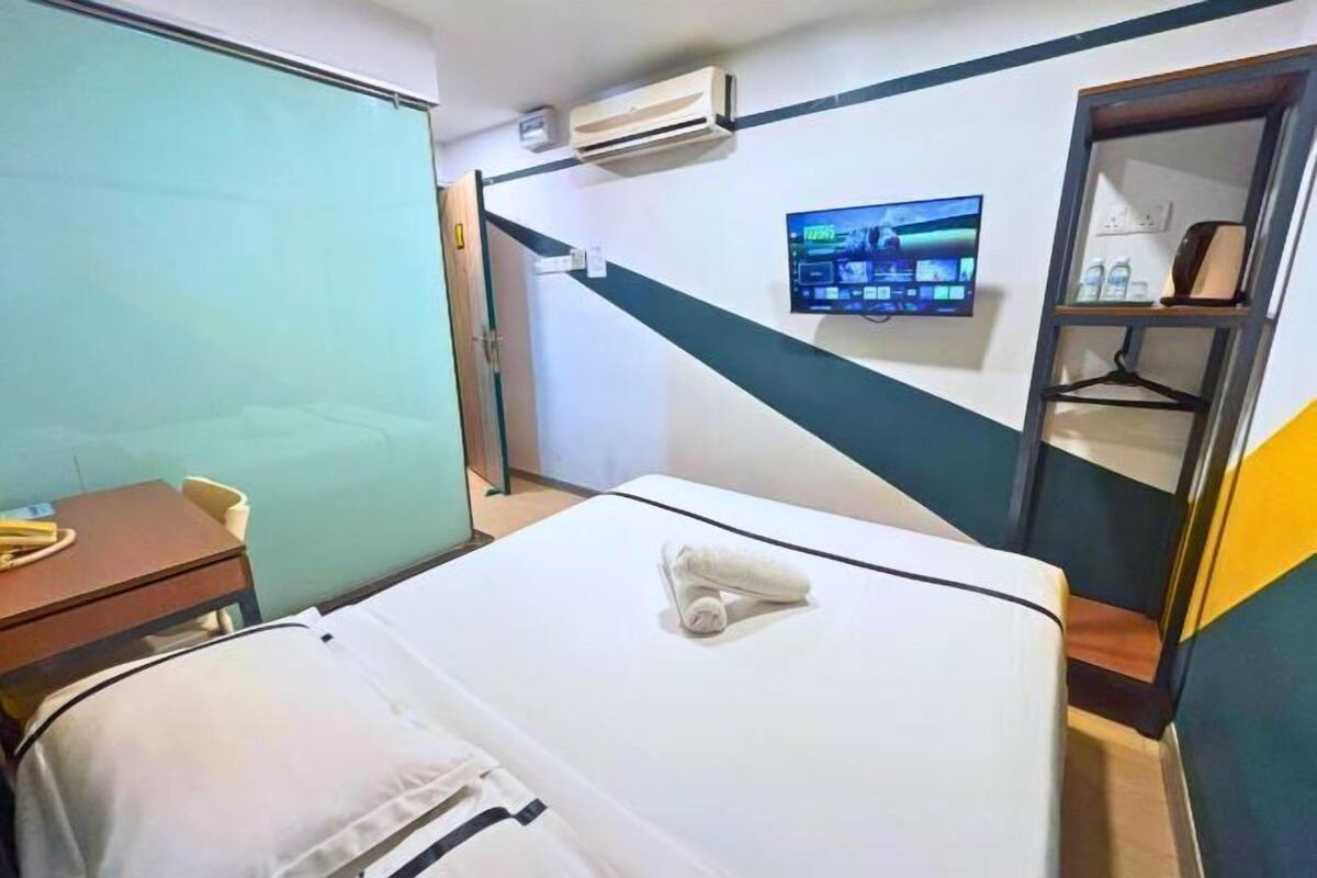 Une chambre d’hôtel équipée d’un lit, d’un bureau, d’une chaise, d’un climatiseur, d’une télévision et d’une armoire.
