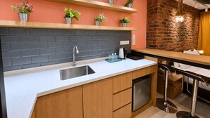 Cucina moderna con parete in mattoni, mobili in legno, lavello in acciaio inossidabile e piante in vaso sugli scaffali.