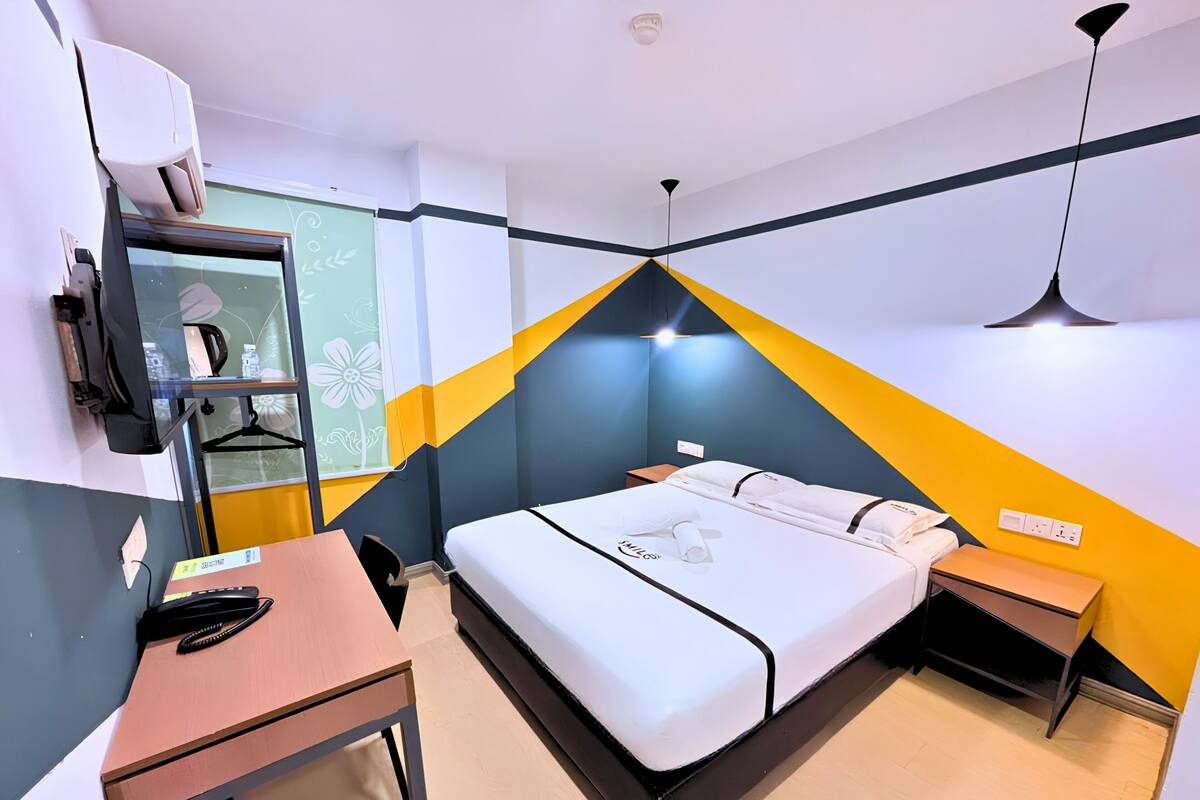 Une chambre d’hôtel moderne équipée d’un lit, de tables de chevet, d’un bureau et d’une chaise.