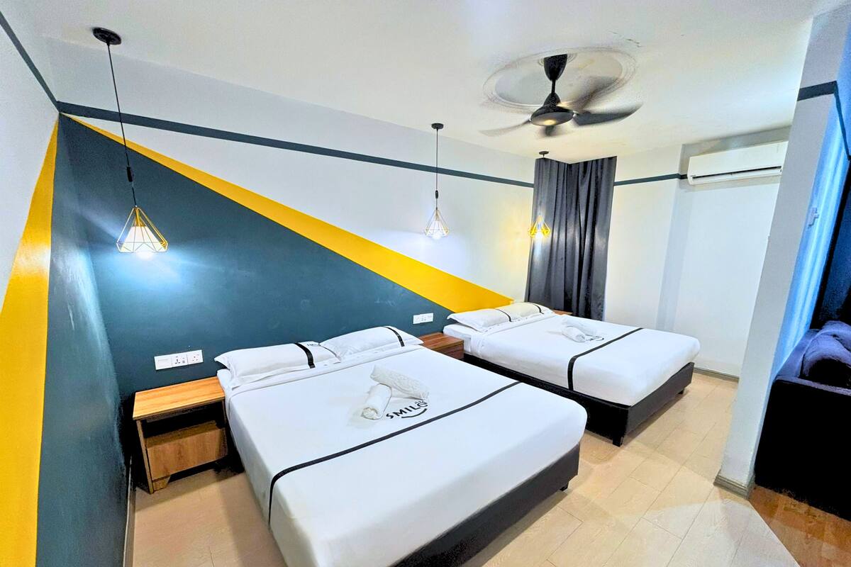 Une chambre d’hôtel avec deux lits, un ventilateur de plafond et un luminaire moderne.