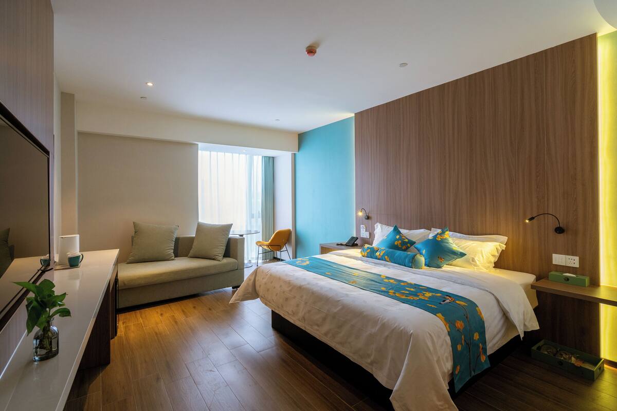 Ett modernt hotellrum med en stor säng, en soffa, ett skrivbord och ett fönster.