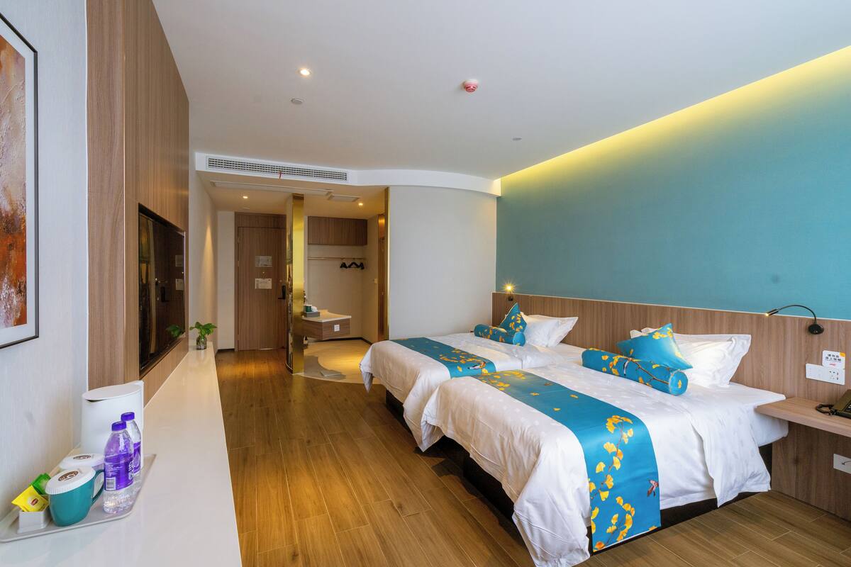 Ett modernt hotellrum med två sängar, en platt-TV, ett badrum och ett litet pentry.