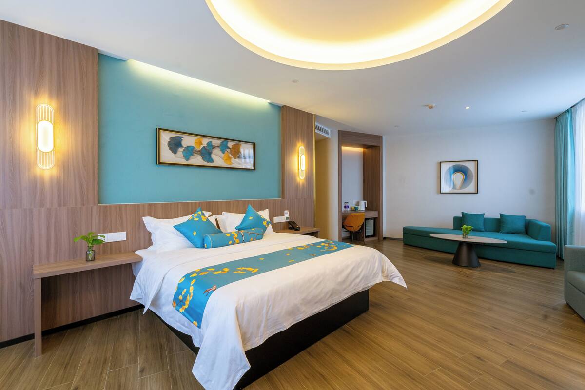 Ett modernt hotellrum med en stor säng, en sittgrupp med soffa, ett litet bord och ett skrivbord.