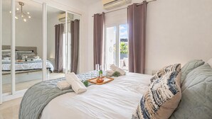 A spacious bedroom with a large bed, a sliding glass door leading to a balcony, and an air conditioning unit on the wall. - Puerto Banus Near La Sala By The Sea (Marbella)