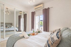 A spacious bedroom with a large bed, a sliding glass door leading to a balcony, and an air conditioning unit on the wall. - Puerto Banus Near La Sala By The Sea (Marbella)