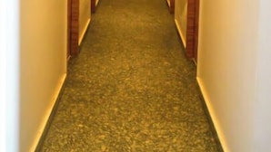Un couloir étroit, dont le sol est recouvert de moquette et où l’on trouve des portes en bois de chaque côté.