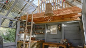 A rustic wooden interior with a sloped ceiling, wooden beams, and a hanging woven basket.
