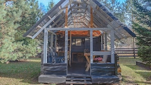 A cabin with a sloped roof, a covered porch, and a small deck area. - Metai Miške&a Year in the Forest (Paliepis)