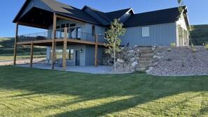 A two-story house with a covered porch and a stone retaining wall. - The Azure View - Sleeps 25 - Pickleball - POOL (Fish Haven)