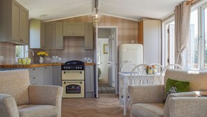 A compact kitchen with a stove, oven, and refrigerator, connected to a dining area with a table and chairs.