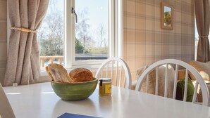A room with a table, a bowl of bread, a jar, and a blue book titled 'cottages.com Guest Book'.