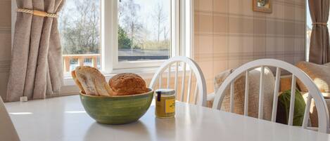 A room with a table, a bowl of bread, a jar, and a blue book titled 'cottages.com Guest Book'.