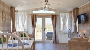 A room with a dining table, chairs, a television, and a view of the outdoors.
