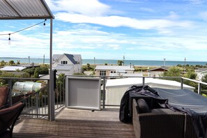 A balcony with a view of the sea, a covered outdoor seating area, and a covered grill. - Seascape Retreat, breathtaking sea views. (Riverton / Aparima)