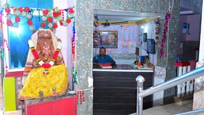 A reception area with a man seated behind a counter, a clock, and a sign indicating 'RECEPTION'. - DhamStay Hotel Beach Heaven Puri (Puri)