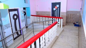 A staircase with a red handrail, a tiled floor, and a door with a geometric design. - DhamStay Hotel Beach Heaven Puri (Puri)