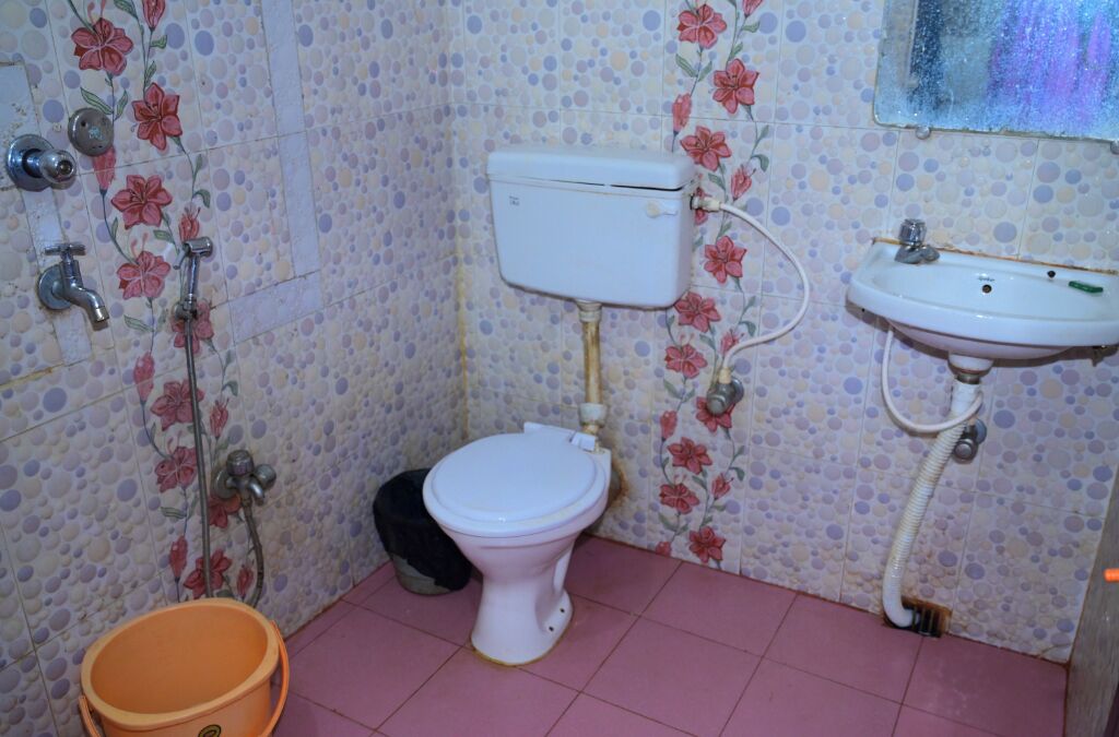 Et badeværelse med toilet, vask og bruser.