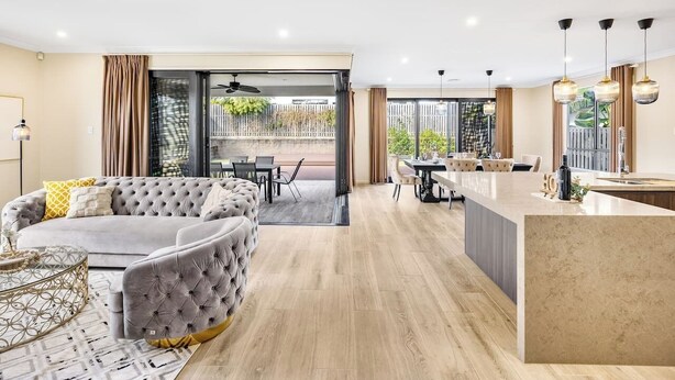 A modern living room with a sofa, a dining area, and a kitchen with a marble countertop.