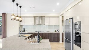 A modern kitchen with a central island, stainless steel appliances, and pendant lighting.